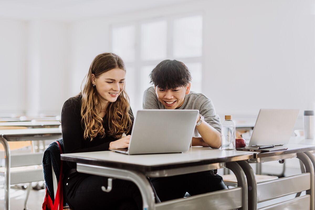 Illustration: Zwei Studierende schauen gemeinsam auf einen Laptop