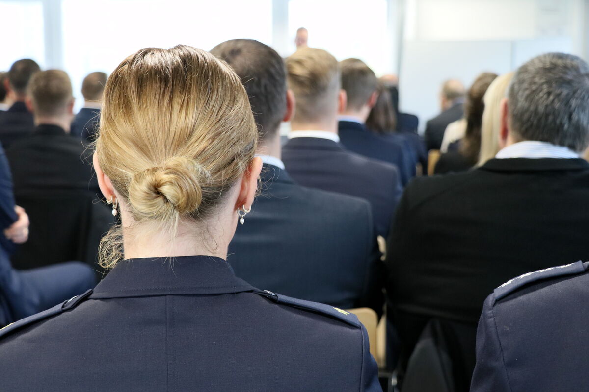 Eine Frau im Anzug sitzt vor einer Gruppe von Menschen.