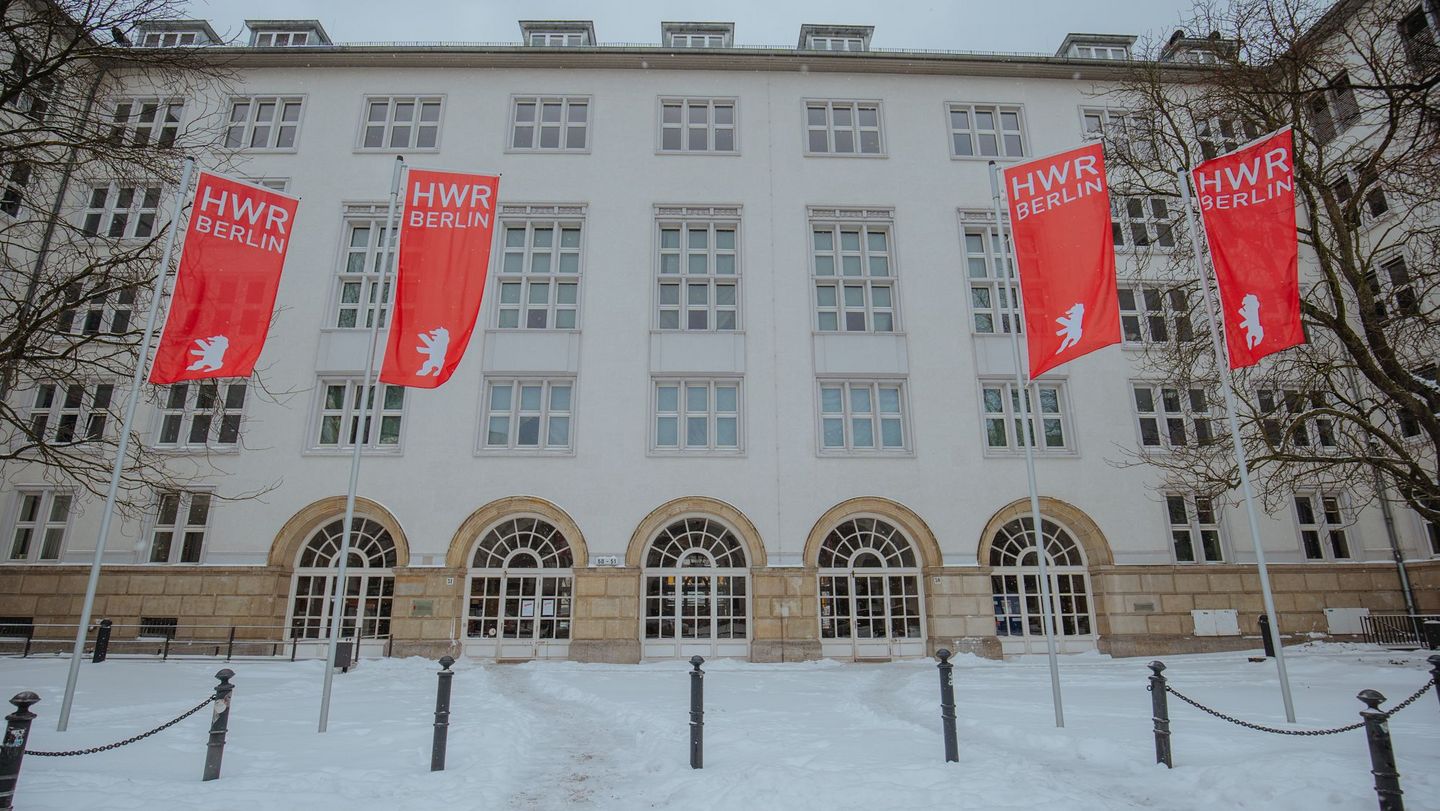 [Translate to English:] Weißes Gebäude im Schnee mit vier Fahnen. 