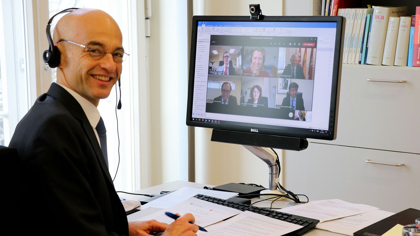 Man sitting at desk in front of screen on which a video conference is running. Photo: Sykle Schumann, HWR Berlin