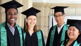 Vier Personen in schwarzen Talaren mit grünen Schärpen und schwarzen Doktorhüten stehen nebeneinander vor einer hellen Wand.