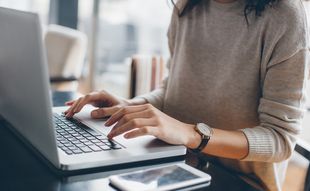 Frau tippt auf einem Laptop.