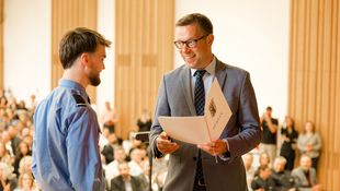 Mann überreicht Urkunde