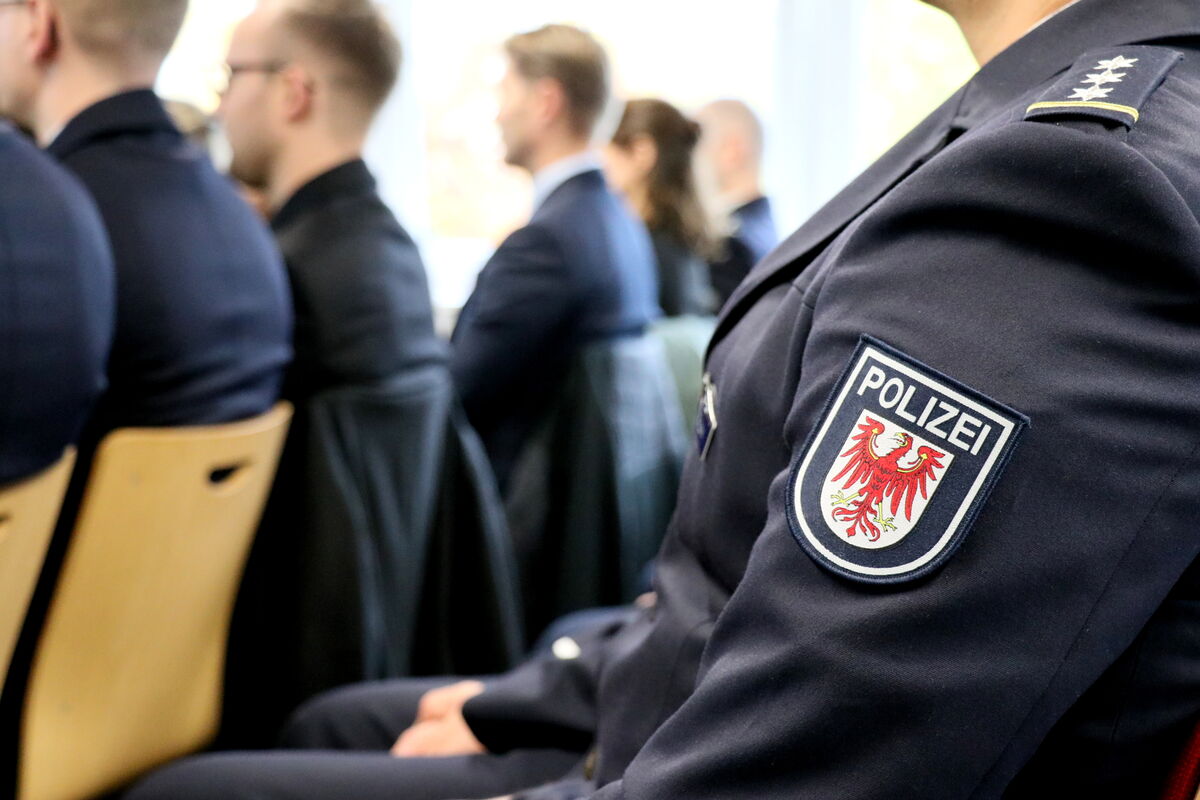 Ein Polizist in Uniform sitzt in einer Gruppe von Menschen.