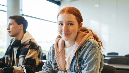 Schülerin sitzt in einem Klassenraum an einem Tisch. 