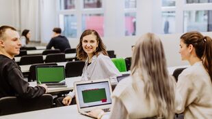 Studierende sitzen in einem Seminarraum mit ihren Laptops