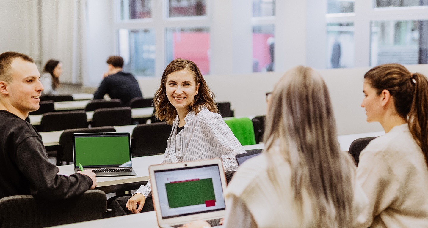 Studierende sitzen in einem Seminarraum mit ihren Laptops